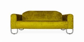 groene velours bank in een eclectisch interieur met Bauhaus accessoires, geometrisch vloerkleed, chromen meubels, designlampen en groene planten.